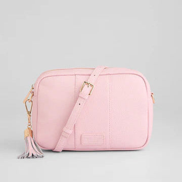 Pink crossbody bag with a tassel on a light gray background