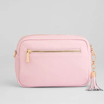 Pink crossbody bag with a gold zipper and tassel on a light gray background