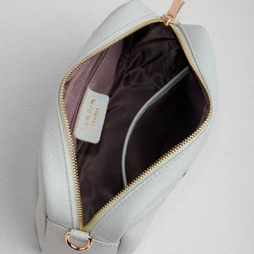 Light gray leather bag with gold zipper on a light gray background
