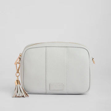Light gray crossbody bag with a tassel on a light gray background