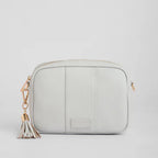 Light gray crossbody bag with a tassel on a light gray background