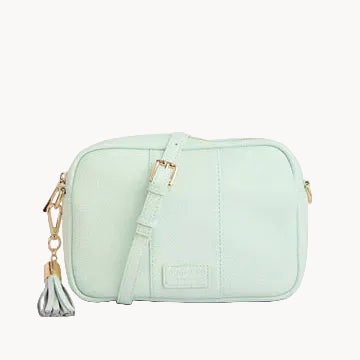 Mint green crossbody bag with a tassel on a light gray background