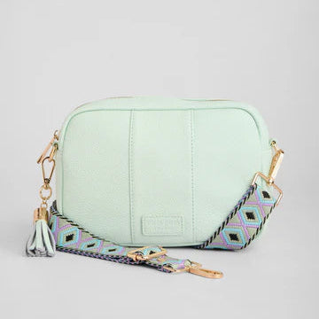 Mint green handbag with a patterned strap on a light gray background