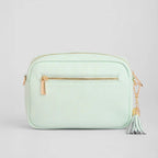 Mint green handbag with gold zipper and tassel on a light gray background