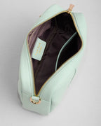 Light green handbag with gold zipper on a light gray background