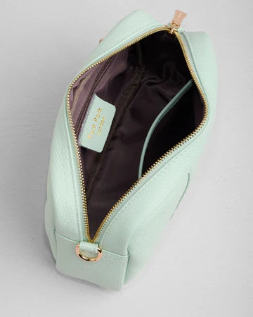 Light green handbag with gold zipper on a light gray background