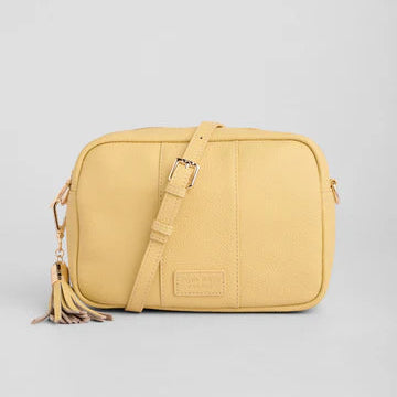 Yellow crossbody bag with a tassel on a light gray background
