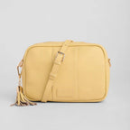 Yellow crossbody bag with a tassel on a light gray background