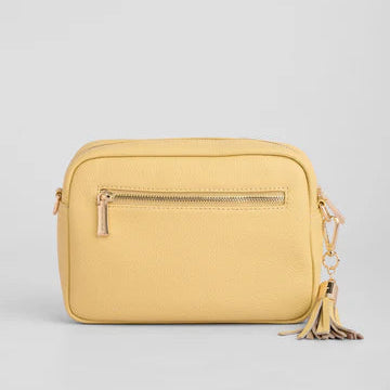 Yellow crossbody bag with a tassel on a light gray background