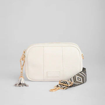 White handbag with a patterned strap on a light gray background