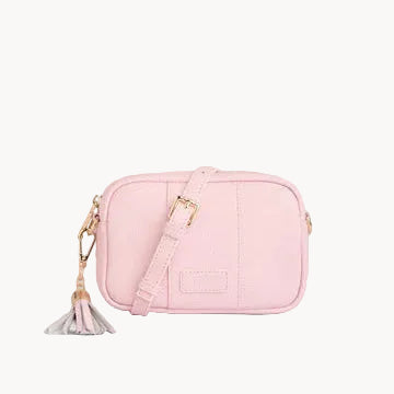 Pink crossbody bag with a tassel on a gray background