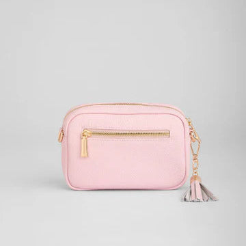 Pink crossbody bag with gold zipper and tassel on a light gray background