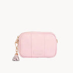 Pink leather bag with a tassel on a light gray background