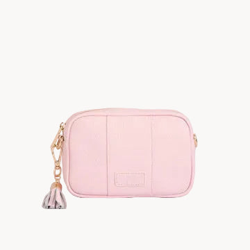 Pink leather bag with a tassel on a light gray background