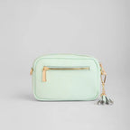 Mint green handbag with a gold zipper and tassel on a light gray background