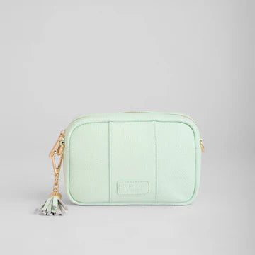 Light green crossbody bag with a tassel on a gray background