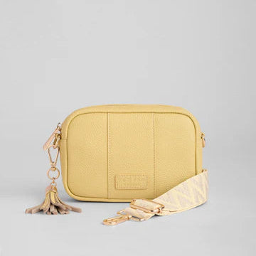 Yellow crossbody bag with a tassel on a light gray background