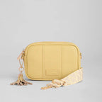 Yellow crossbody bag with a tassel on a light gray background