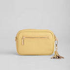 Yellow crossbody bag with a tassel on a light gray background