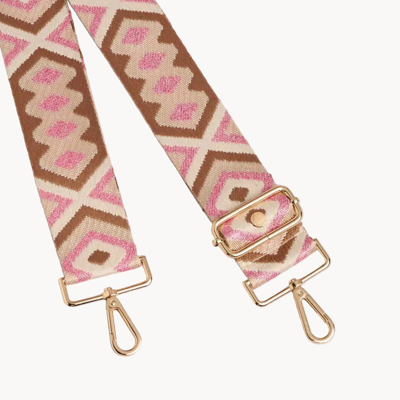 Patterned bag strap with gold hardware on a light gray background
