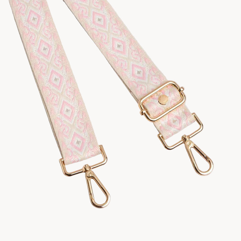 Patterned bag strap with gold hardware on a light gray background