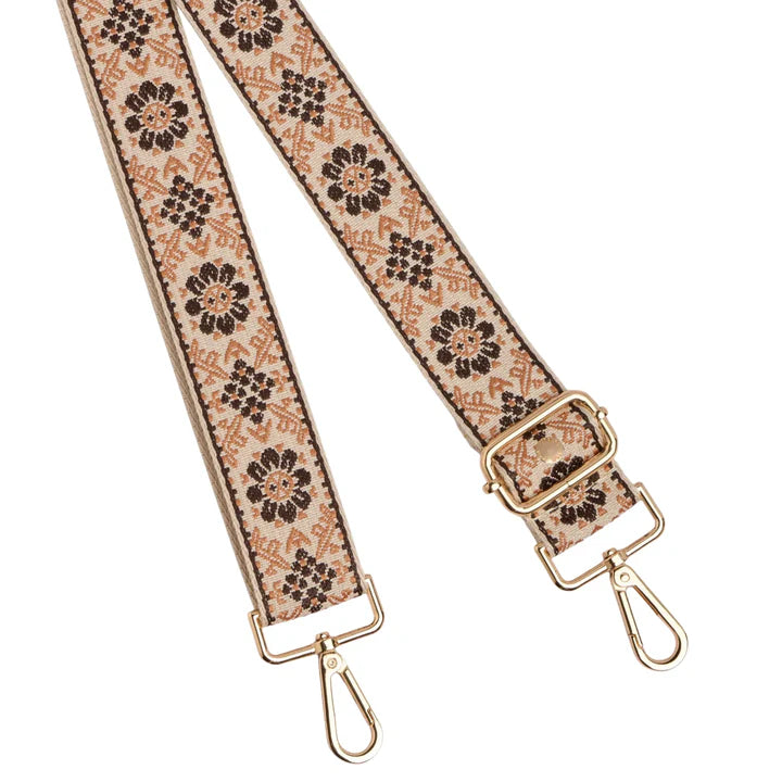 Floral patterned strap with gold hardware on a white background