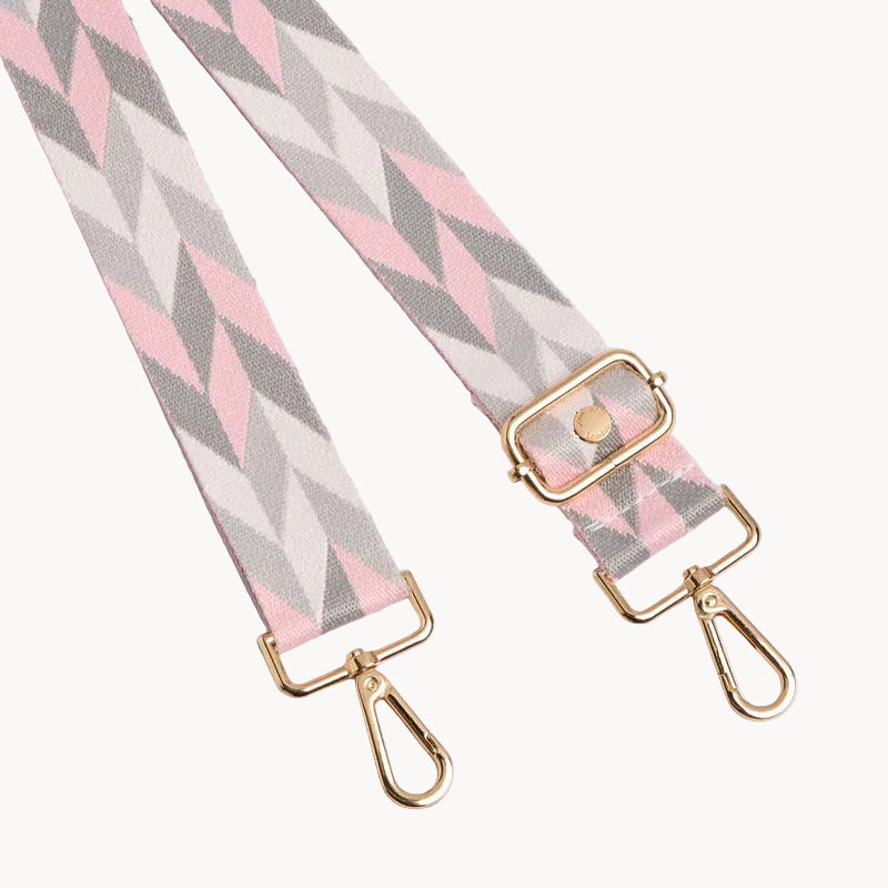 Fabric strap with pink and gray chevron pattern and gold hardware on a light gray background