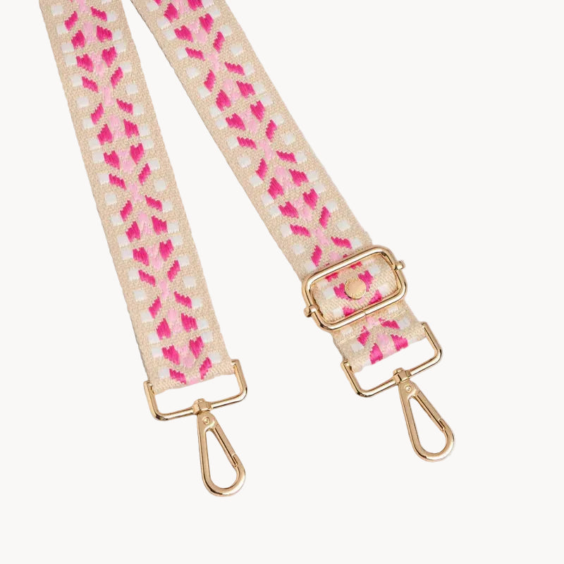Bag strap with pink floral pattern and gold hardware on a light gray background