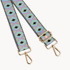 Patterned bag strap with gold hardware on a light gray background