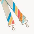 Colorful striped bag strap with gold hardware on a light gray background