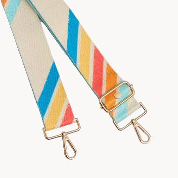 Colorful striped bag strap with gold hardware on a light gray background
