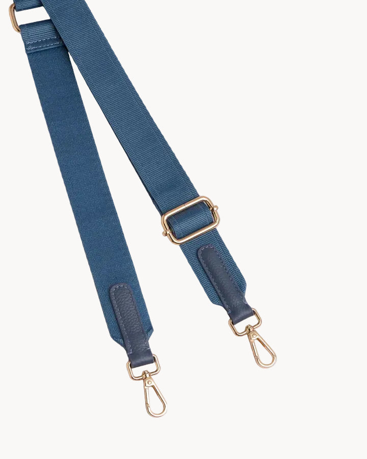 Blue bag strap with gold hardware on a light gray background