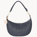 Navy handbag with a pom-pom detail on a white background
