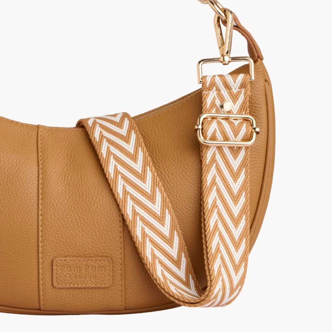 Brown leather handbag with a chevron patterned strap on a gray background