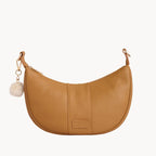 Tan leather handbag with a keychain on a light gray background
