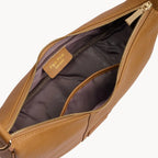 Tan leather bag with gold zipper on a light gray background