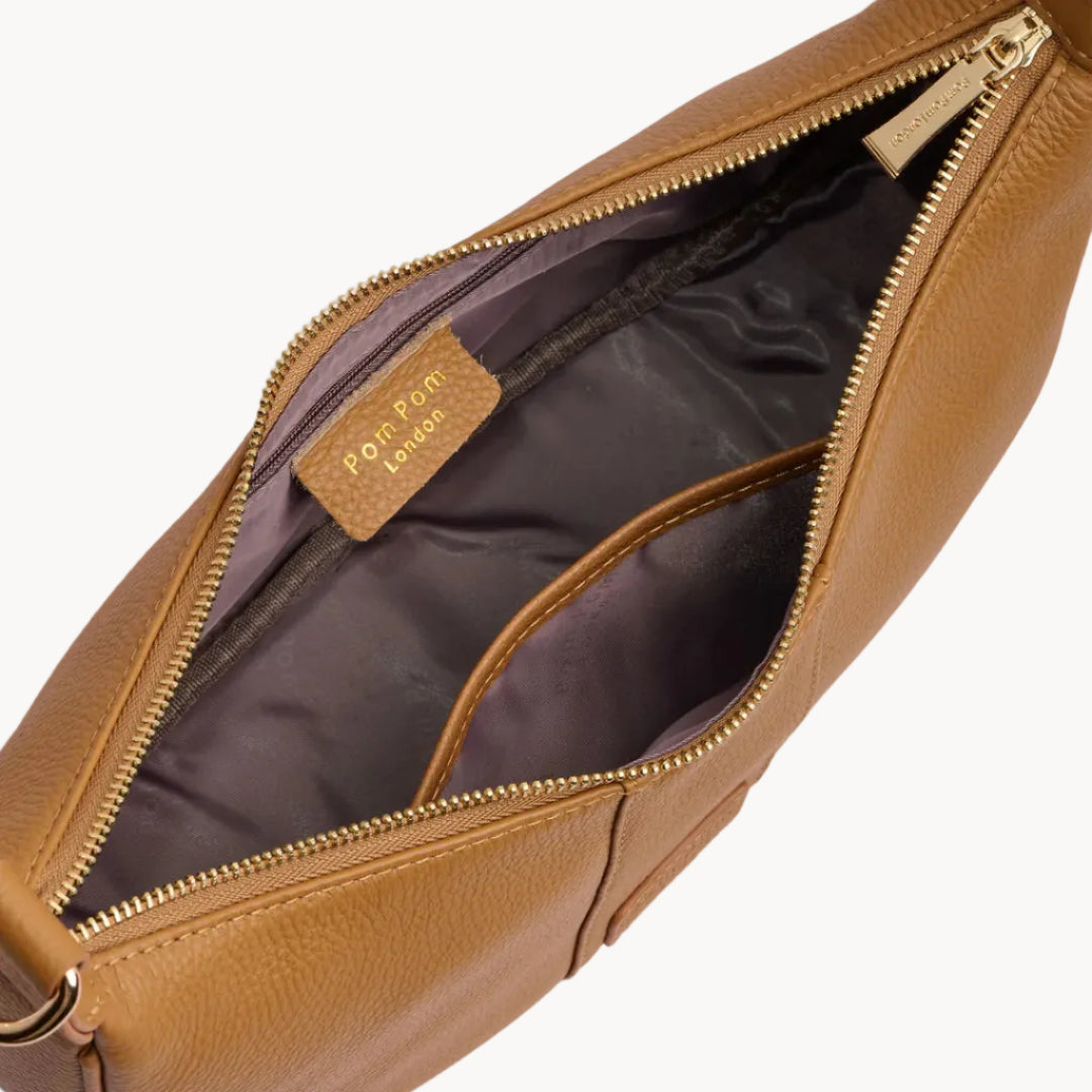 Tan leather bag with gold zipper on a light gray background