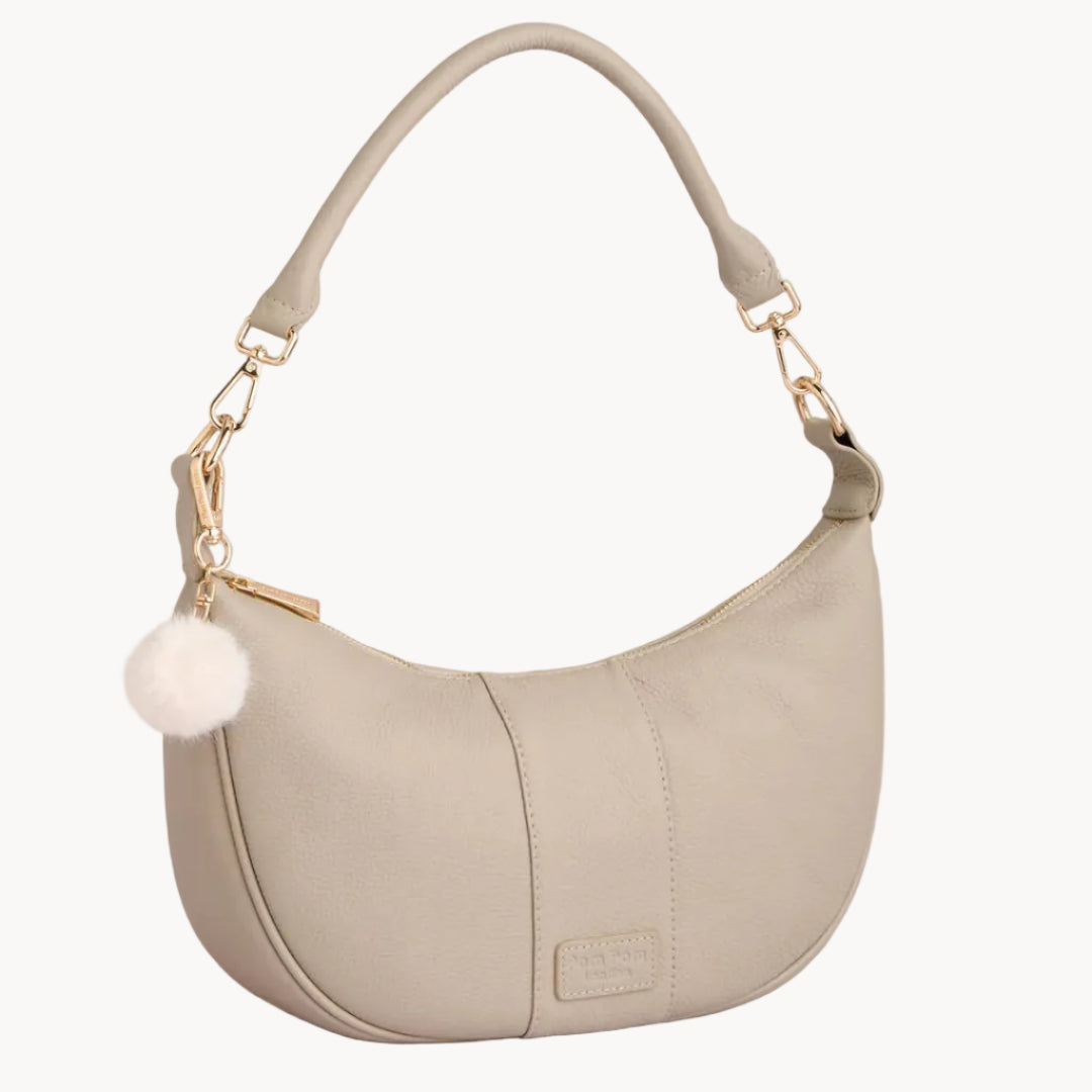 Stone handbag with a gold chain and white pom-pom on a light gray background