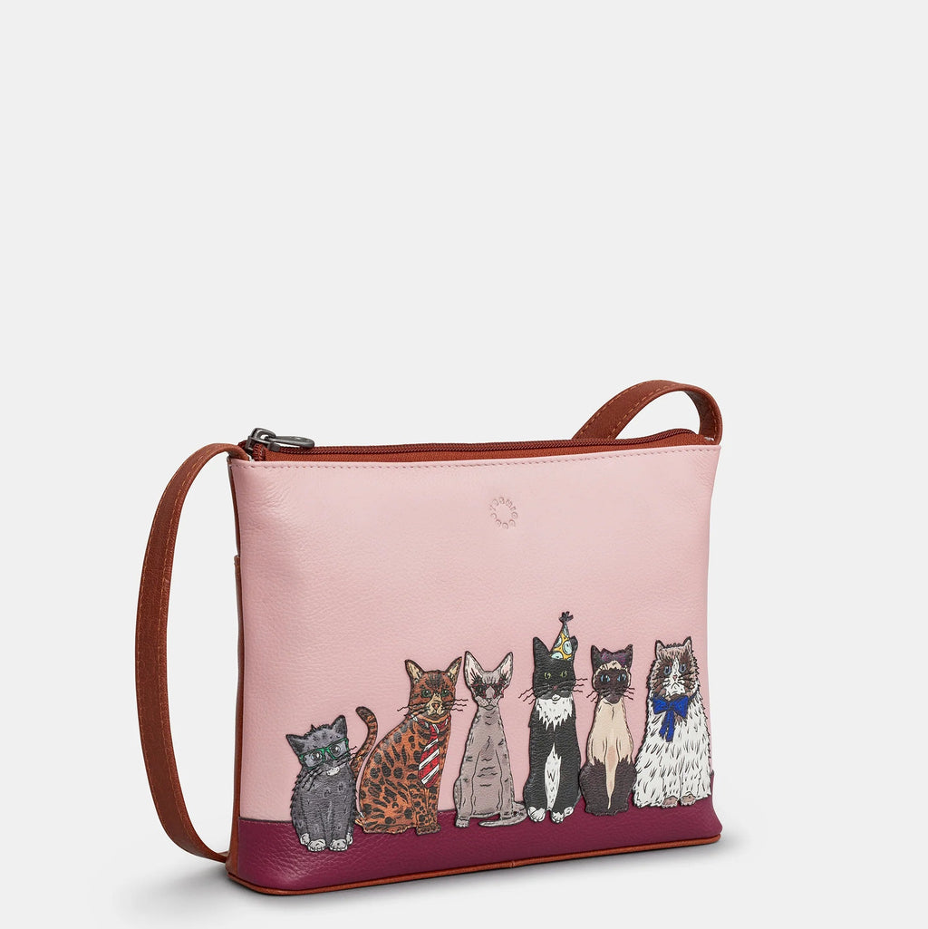 Pink crossbody bag with cat illustrations on a light gray background