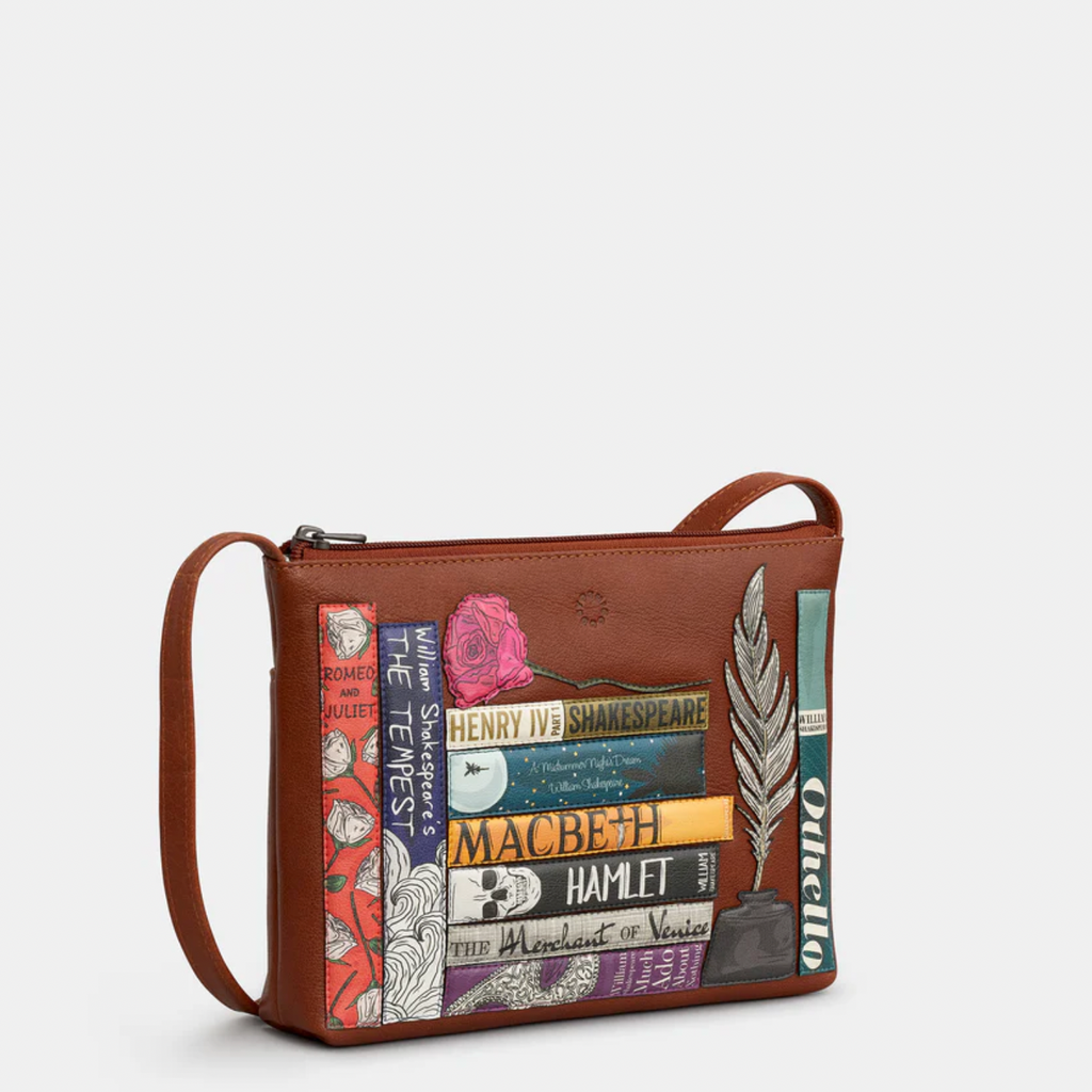 Brown leather crossbody bag with book-themed design on a white background