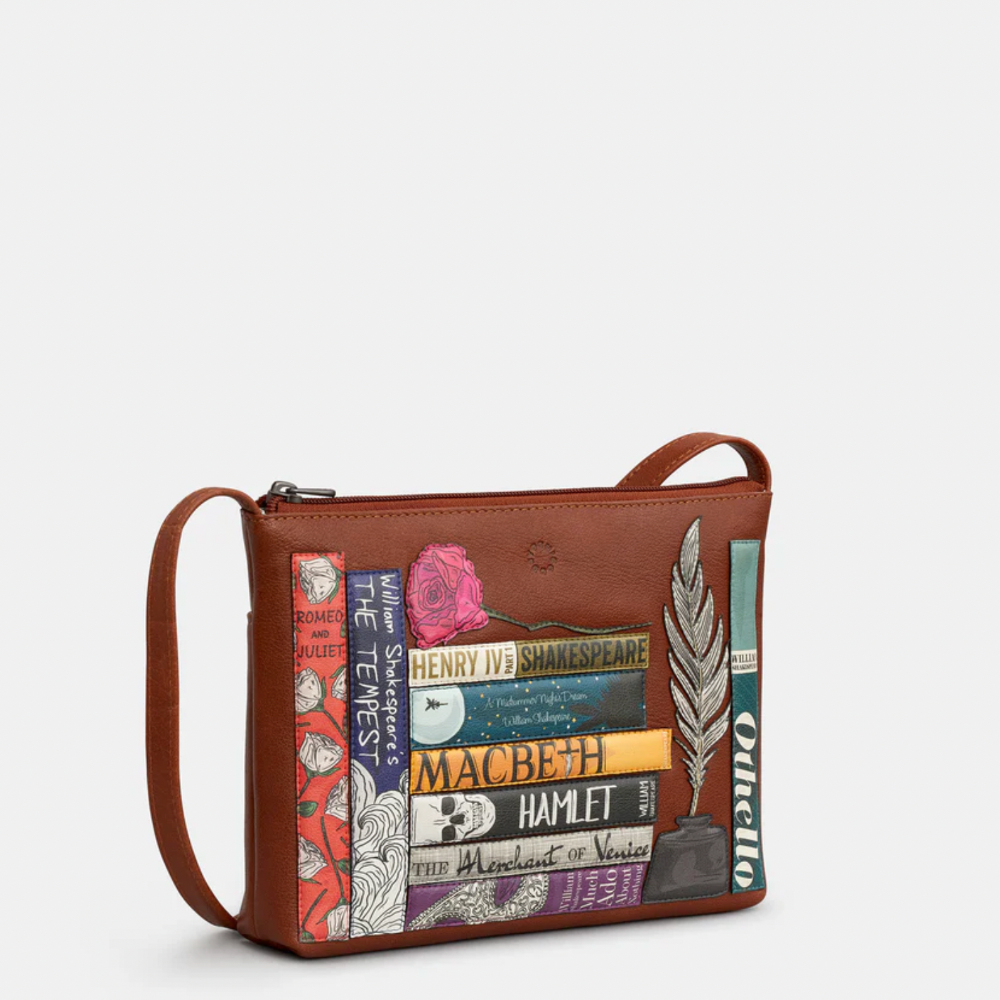 Brown leather crossbody bag with book-themed design on a white background