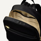 Black backpack with open front compartment showing beige interior.