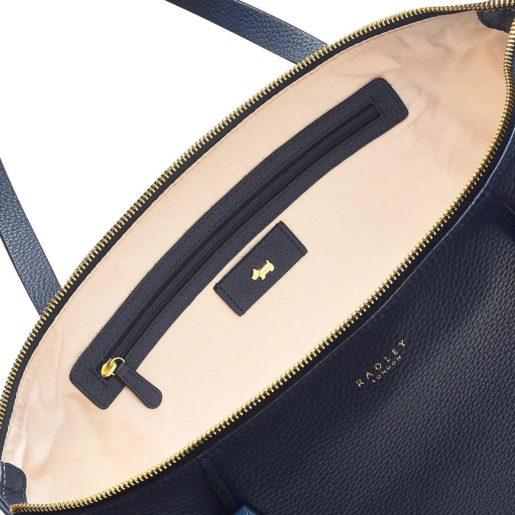 Close-up of a navy blue leather bag with a gold zipper and visible brand name.